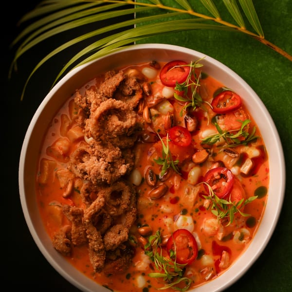 Mikhuna Japanese-Peruvian ceviche with fried calamari, chili, and herbs in a white bowl.
